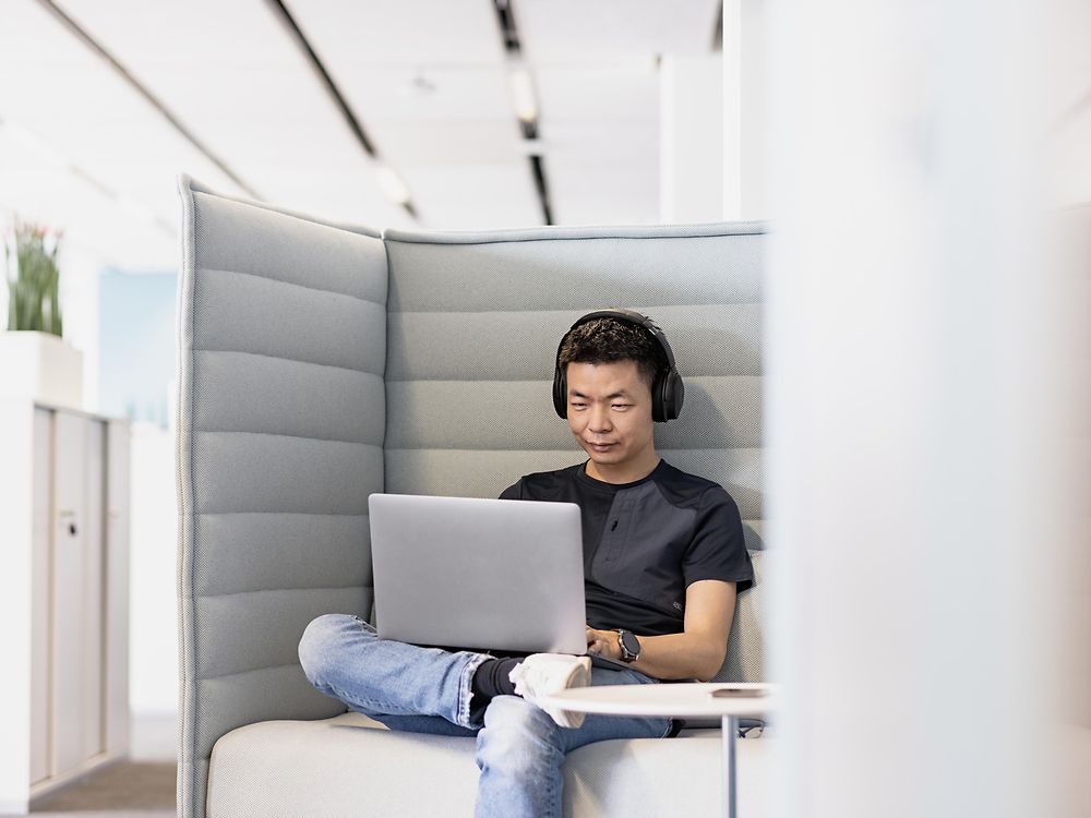 Een Henkel werknemer met hoofdtelefoon werkt geconcentreerd op zijn laptop.