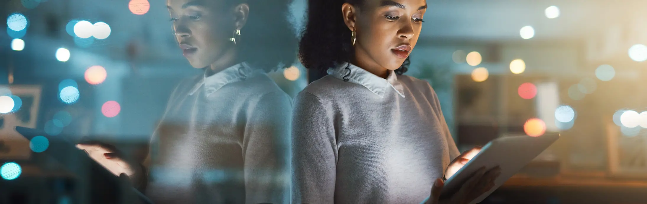 A woman is typing on a tablet, looking focused and concentrated.