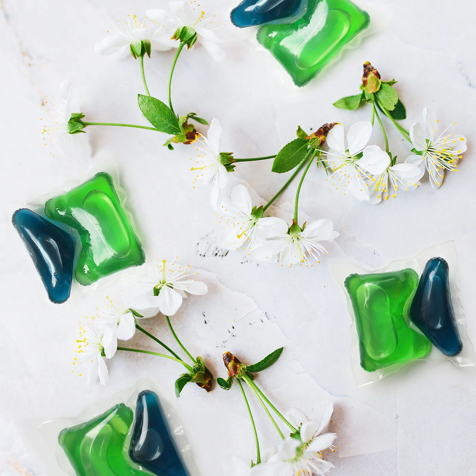 Twee groene en blauwe Henkel Persil tabs met kersenbloesems rondom