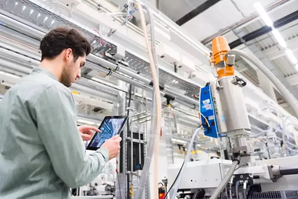 Des ouvriers manipulent des machines à l'intérieur d'une usine de fabrication industrielle.