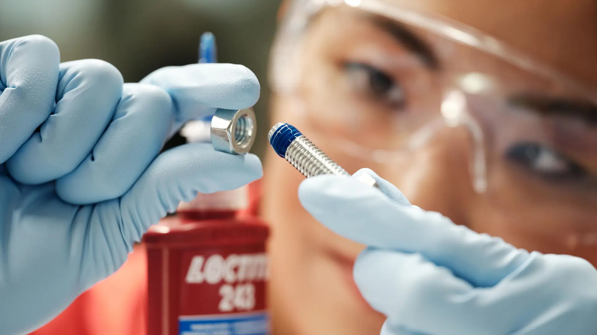 Gros plan sur une personne appliquant un adhésif Loctite sur un boulon, illustrant la précision et l'innovation qui caractérisent l'activité adhésifs industriels de Henkel.