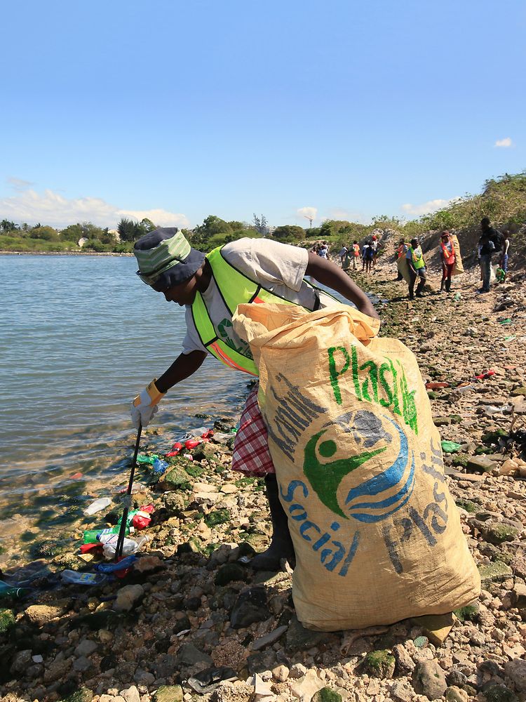Une femme collectent des déchets plastiques en Haiti
